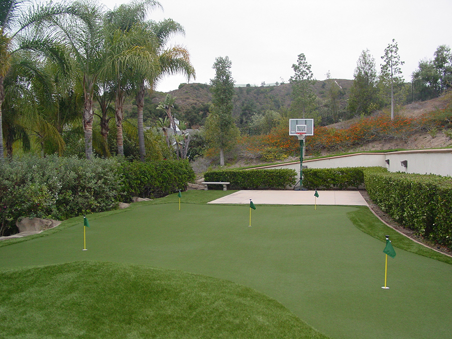 Artificial turf backyard putting green with basketball court.