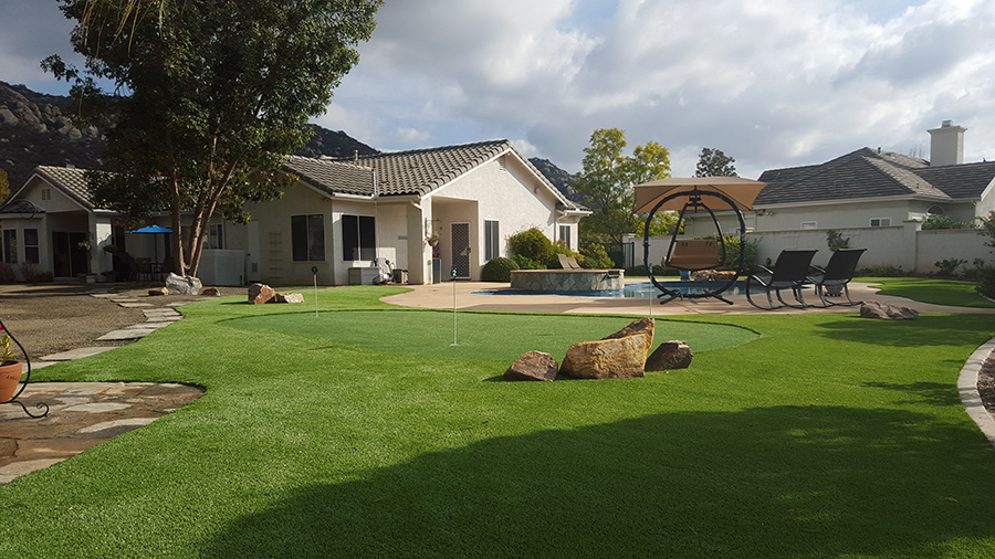 Turf installation in backyard with artificial grass putting green.
